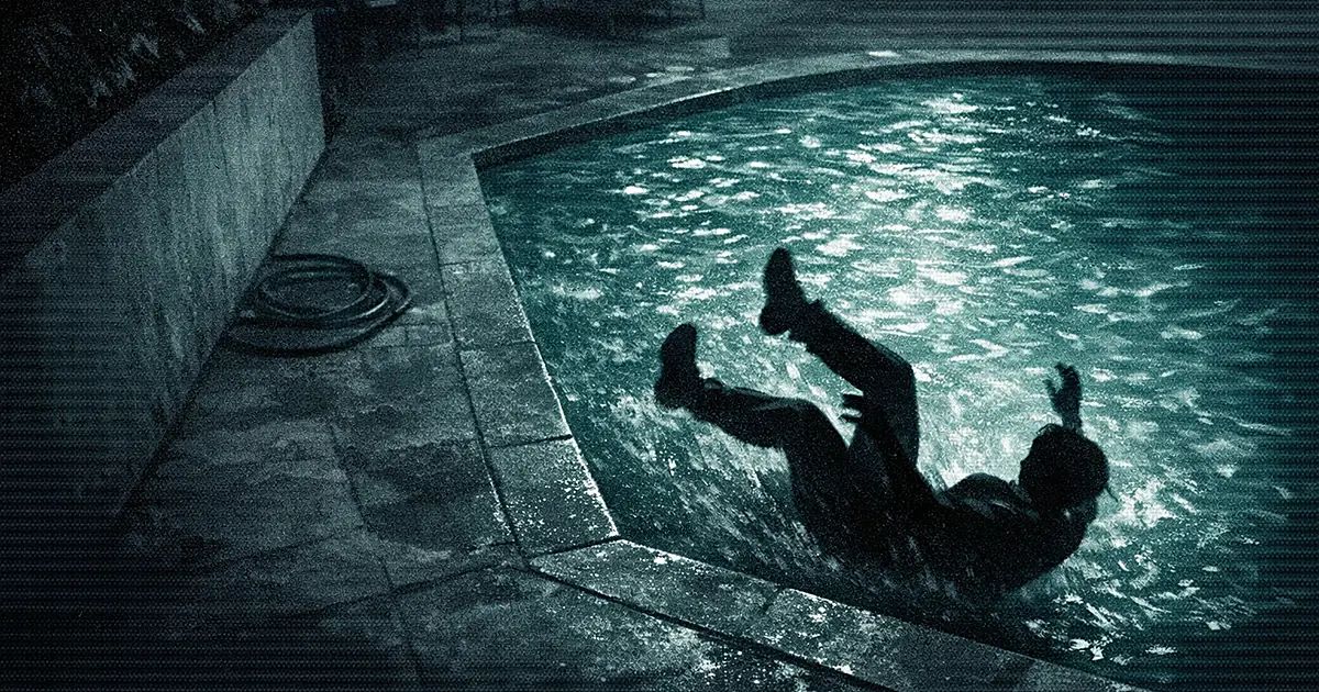 High-angle view of silhouetted figure falling backward into illuminated pool at night in surveillance camera style