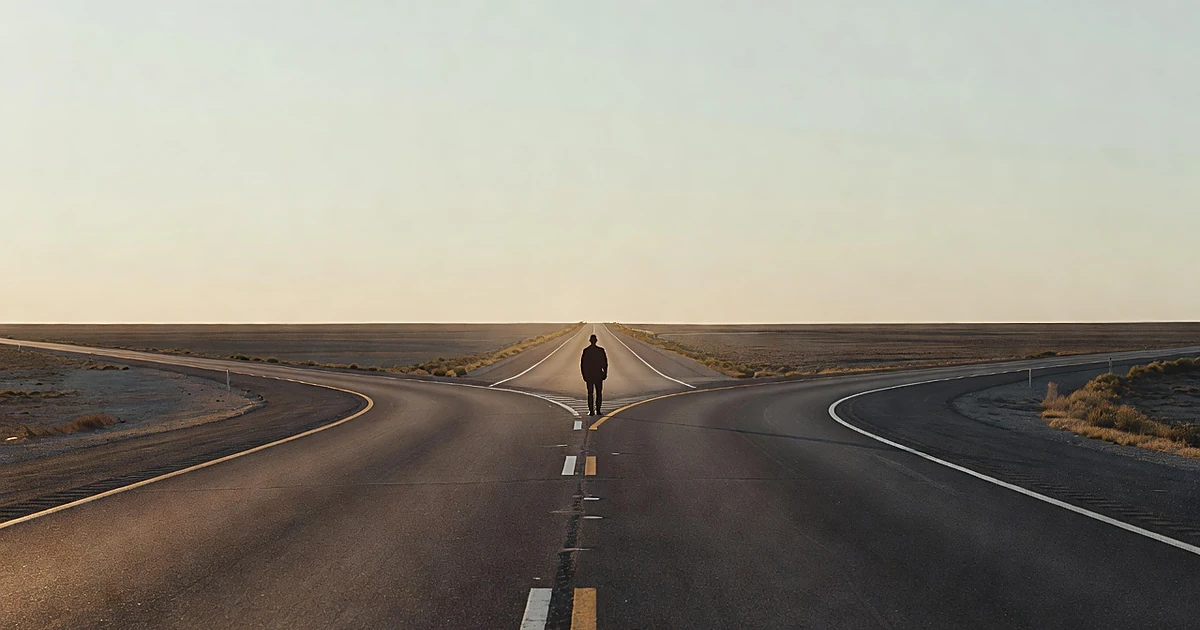 Silhouetted figure at fork in highway with open road stretching toward horizon under expansive sky